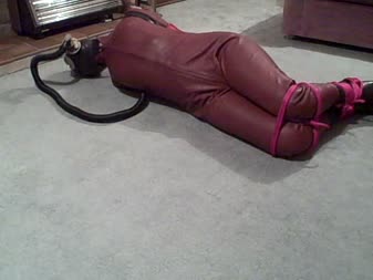 Karina Is Bound In A Leather Catsuit Rubber Armbinder And Gas M - We return to see karina has a rubber armbinder added over her leather catsuit.  The leather hood has been replaced by a rubber hood over which a gas mask has been fitted.
her legs are tied off to the bottom of the armbinder forcing her into a hogtie.  Ropes encircle her ankles and knees.
karina's predicament is heightened by a length of rubber hose being added to her gas mask.  She makes unusual noises as she breathes in and out.  Another length of tubing is added making breathing very difficult.