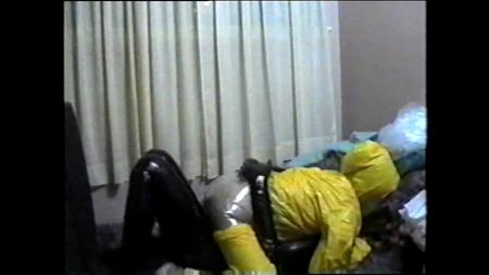 Yellow Rain Headbag And Black Vinyl Zentai - In this clip, the instructor dons a black stretch vinyl zentai, and acolyte "e" a yellow, hooded vinyl rain suit and heavy rubber female mask. The instructor takes her from behind, and then out comes a 6 foot long clear plastic dry cleaning bag. They switch positions as she climbs aboard, and out comes the bag again. At last, her prayers are answered.