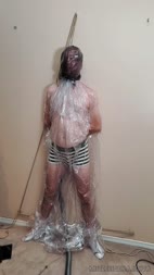 Hanging Body Vacuum Bag - How much would you give to be in this slaves place? Sealed inside a large clear plastic bag and a further plastic hood is placed over his head. 

Mistress Bella fixes a rope around his neck and pulls down forcing him onto his toes whilst she places the vibrator on his cock.